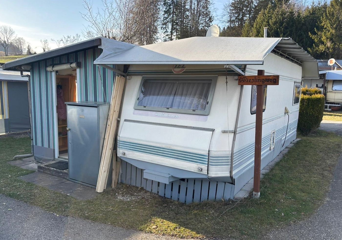 Alter Wohnwagen mit festem Holzvorbau auf einer Dauercamping-Parzelle